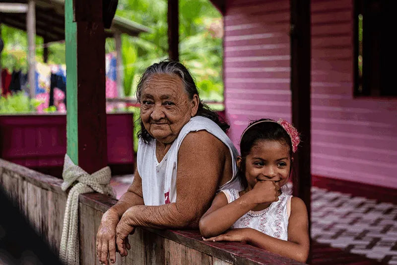 Amazonian grandmother and child representing generations of families involved in sustainable açaí cultivation, reinforcing community, tradition, and the fair trade values behind Tupan Açaí Coffee.